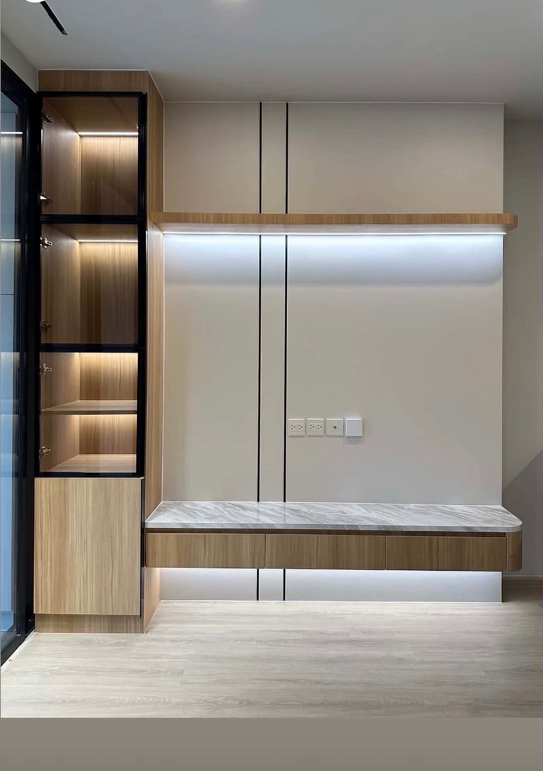 Modern built-in wall unit with illuminated wooden shelving, frosted glass doors, and marble countertop in minimalist bedroom design.