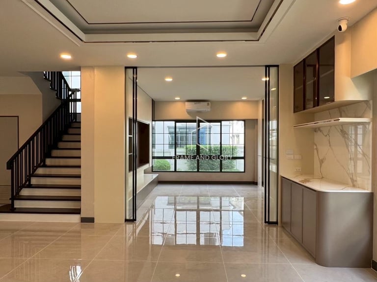 Modern open-concept kitchen and living area with staircase, glass doors, marble flooring, and recessed lighting