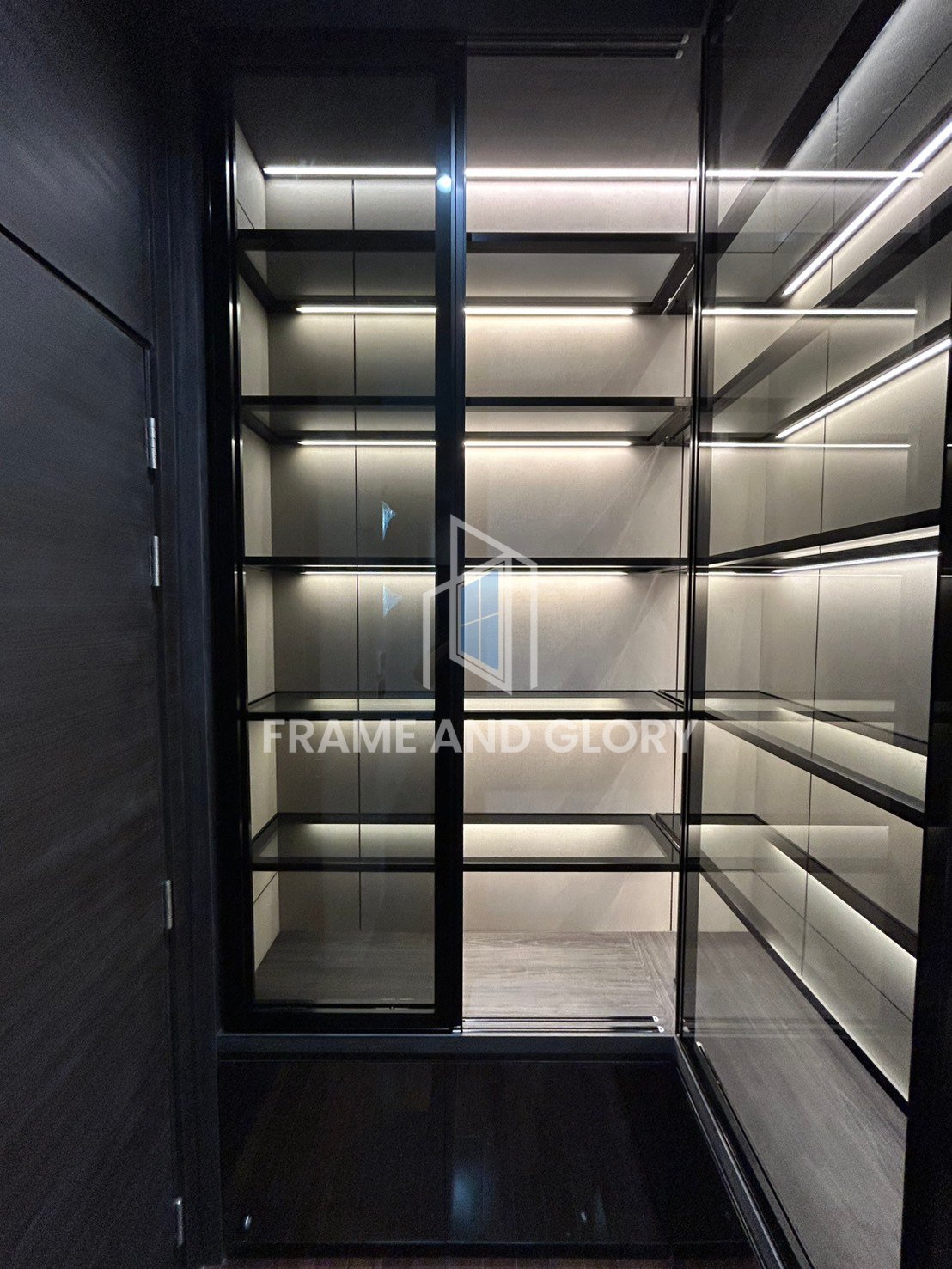 Empty glass display refrigerator with illuminated shelves and black frame viewed from inside