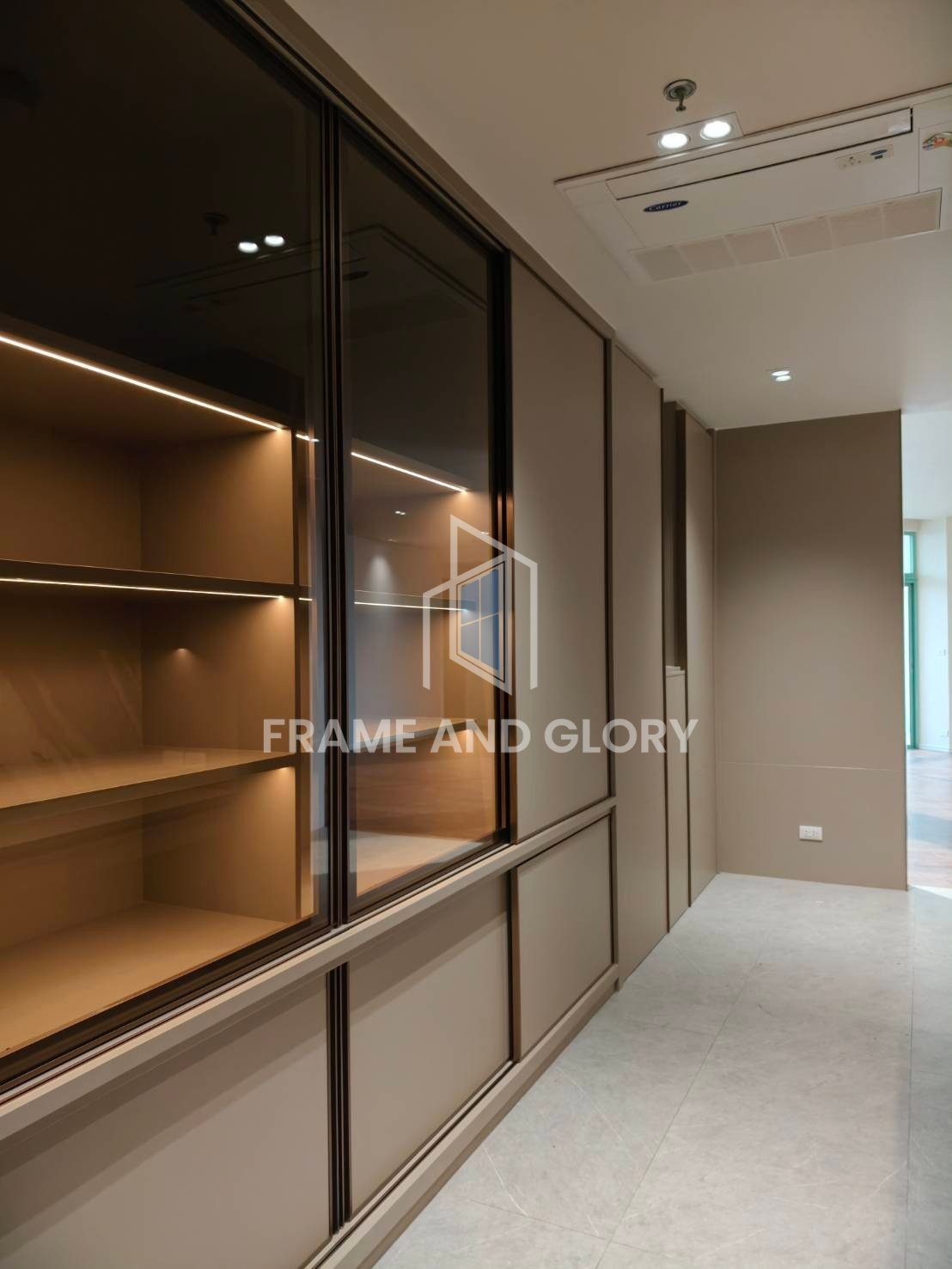 Modern hallway with floor-to-ceiling glass and black-framed display cabinets with warm interior lighting