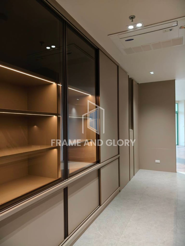 Modern hallway with floor-to-ceiling glass and black-framed display cabinets with warm interior lighting