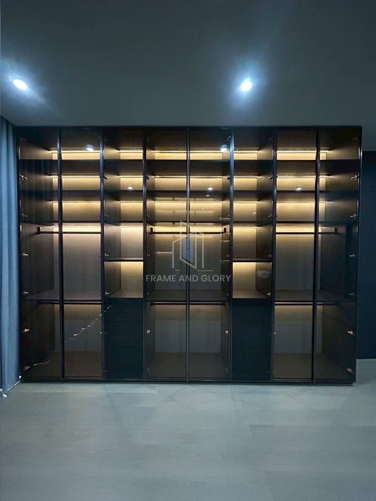Modern black metal shelving unit with illuminated shelves and glass doors in a gallery display setting