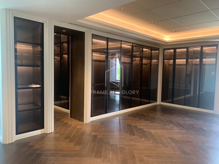 Modern office interior with glass-walled conference rooms, herringbone wood flooring, white trim, and warm ceiling lighting