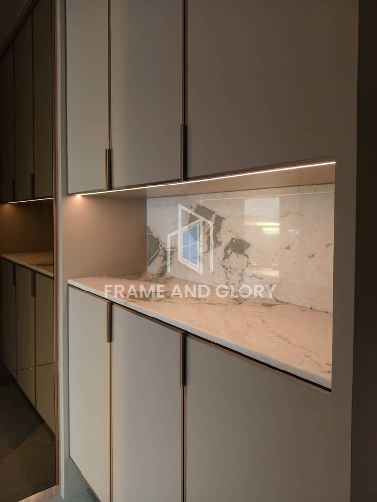 Modern kitchen display showing Frame and Glory branded image on screen set into light wood and white cabinetry