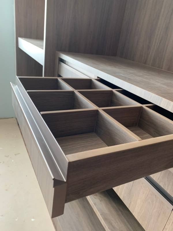 Open wooden dresser drawer with multiple compartments for organizing clothing and accessories