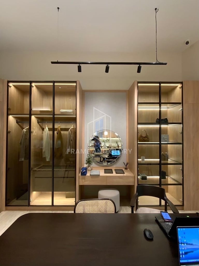 Modern home office workspace with illuminated glass display cabinets, desk setup, and computer equipment mounted on wall